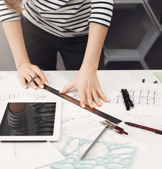 Top view young good looking architect student girl casual striped shirt black jeans standing near table holding ruler pen hands making drawings watching movie digital table gett 1 (1)